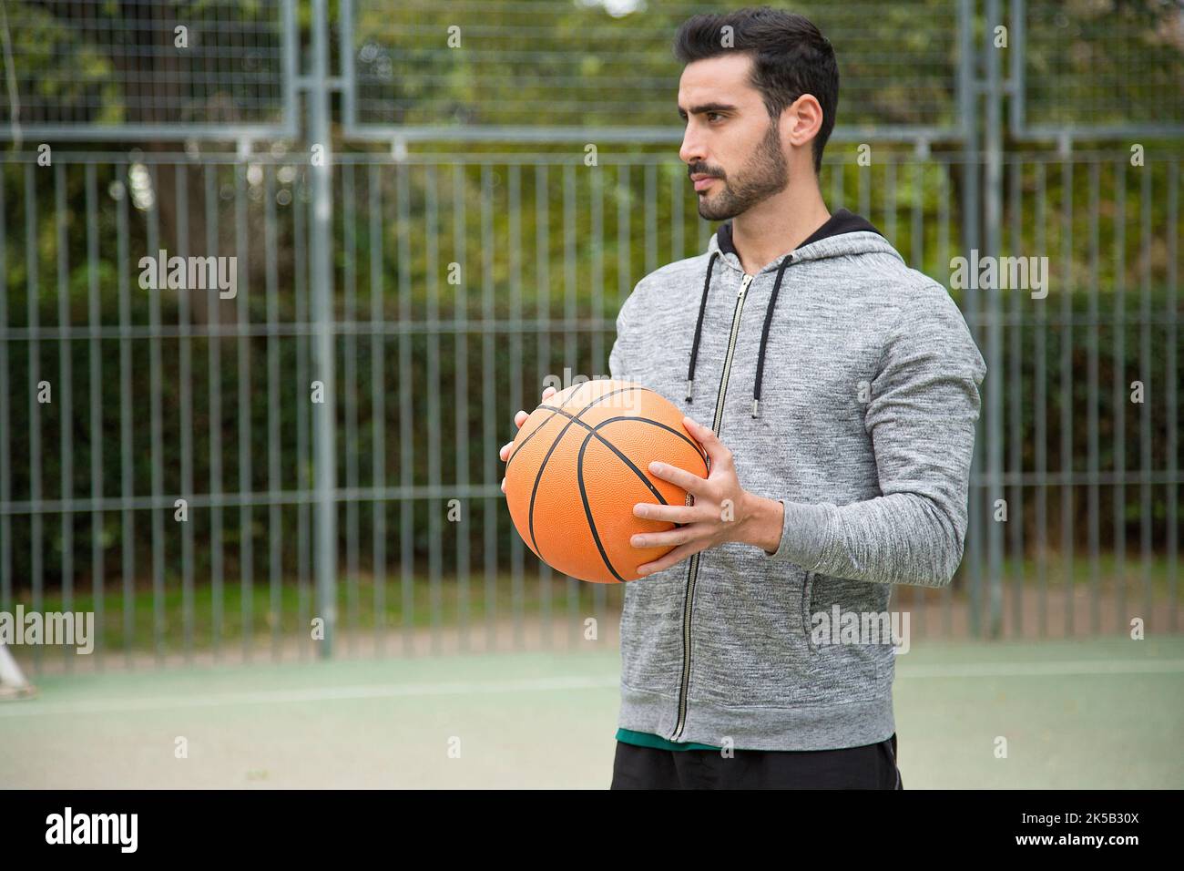 Portrait d'un joueur de basket-ball sportif sur un terrain en plein air au milieu d'un parc Banque D'Images