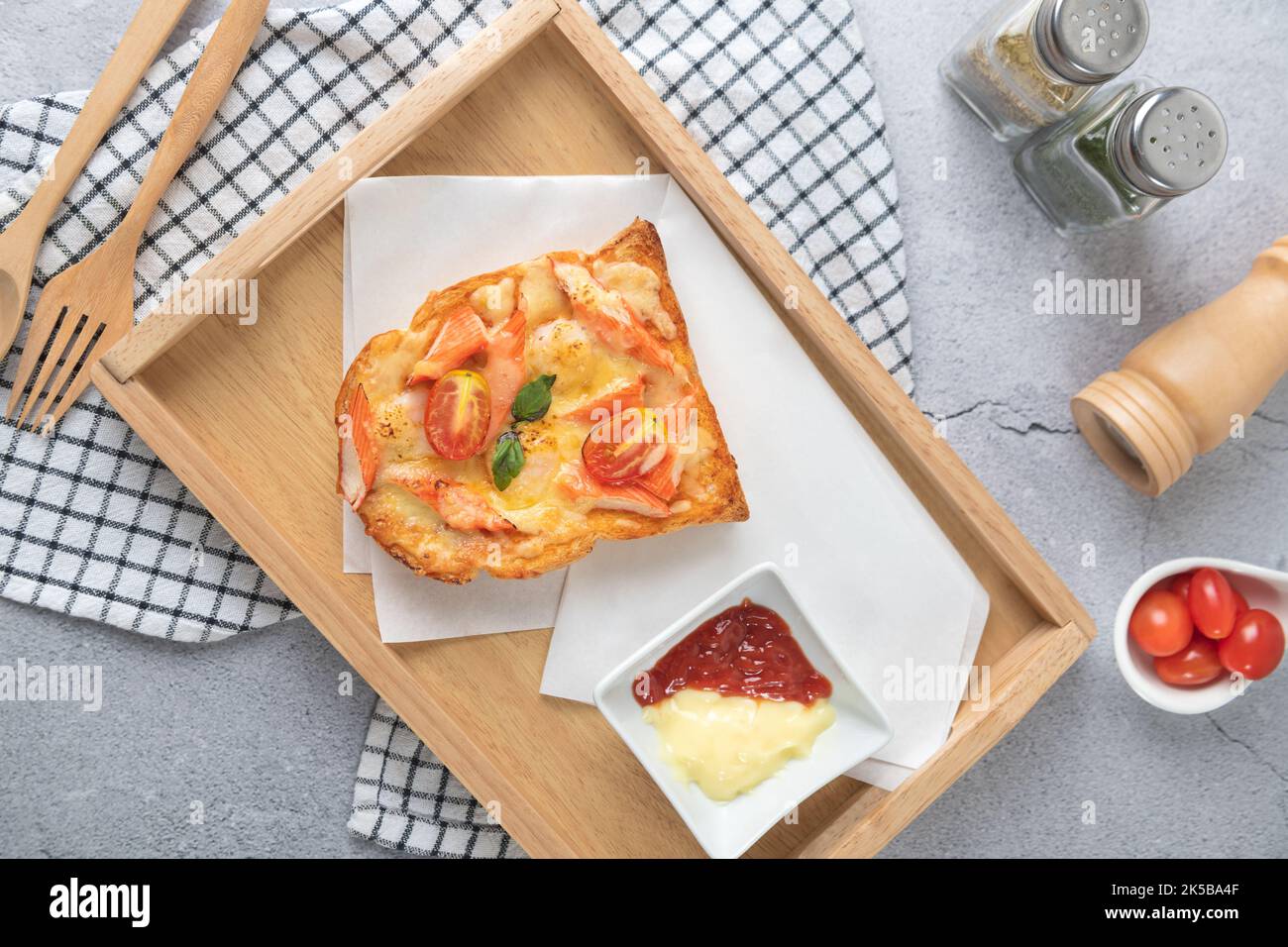 Pain à pizza recouvert de crevettes, bâtonnets de crabe, tomates, fromage dans un plateau en bois avec sauce vue sur le dessus Banque D'Images