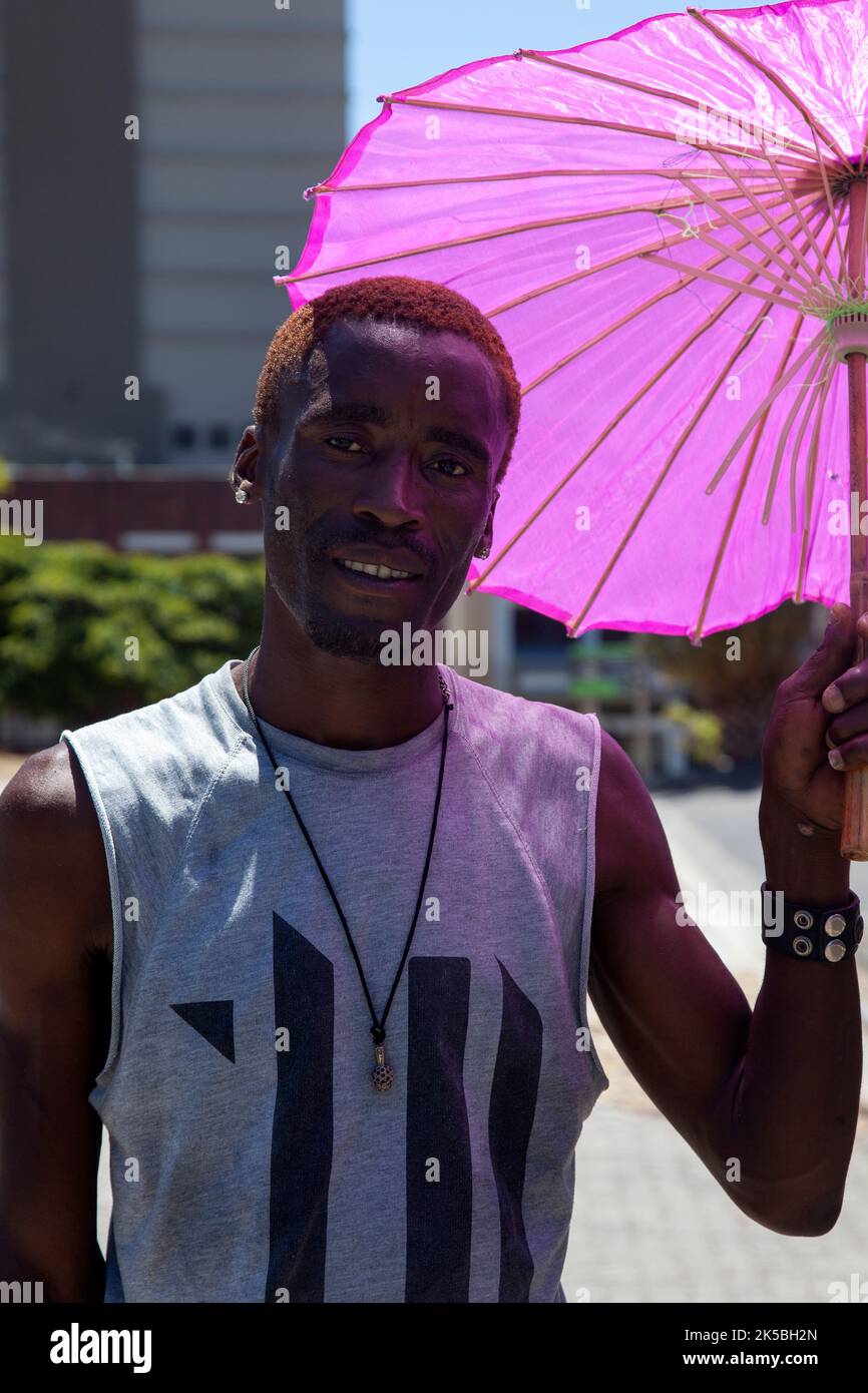 Homme au Cap tenant un parasol rose - Afrique du Sud Banque D'Images