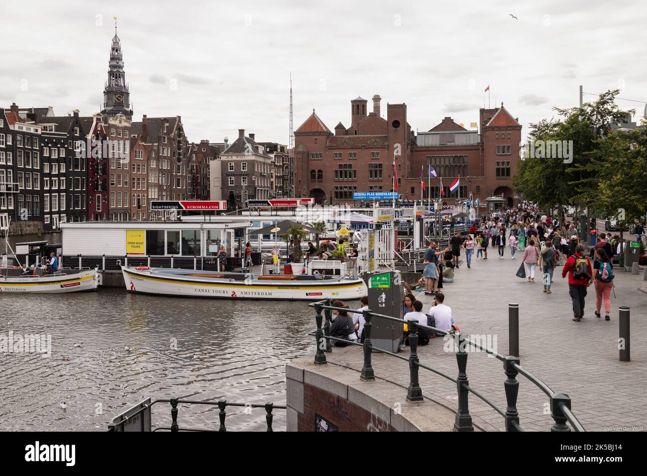 Les résidents et les touristes se promènent le long des croisières sur le canal sur le Damrak dans le centre d'Amsterdam. Banque D'Images