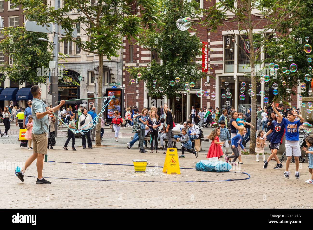 Souffleur à bulles avec des enfants heureux sur une place dans le centre d'Amsterdam. Banque D'Images