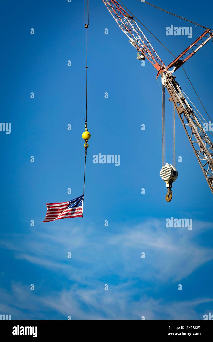 Un drapeau, suspendu à une grue, se déporte dans le vent au-dessus de Manitowoc, Wisconsin. Banque D'Images