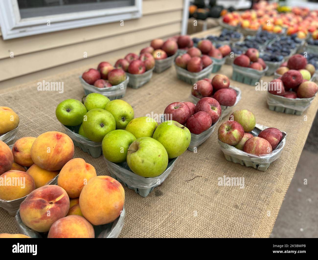 Paniers de pêches et de pommes fraîchement cueillies à vendre sur un stand de ferme situé en bordure de route à New York en automne. Banque D'Images