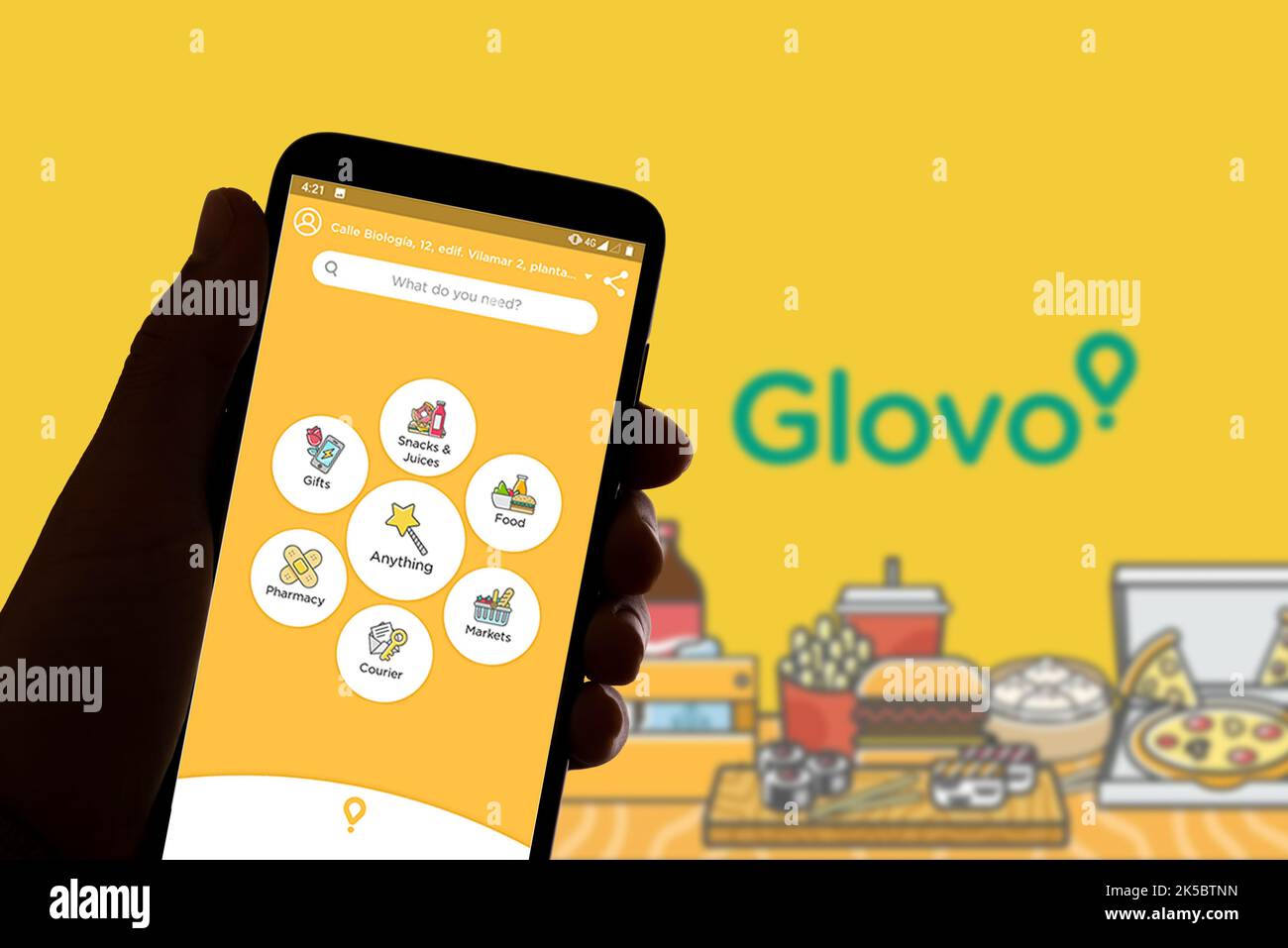 Sur cette photo, le logo du service de livraison de nourriture Glovo est visible sur l'écran du téléphone portable et en arrière-plan. Banque D'Images