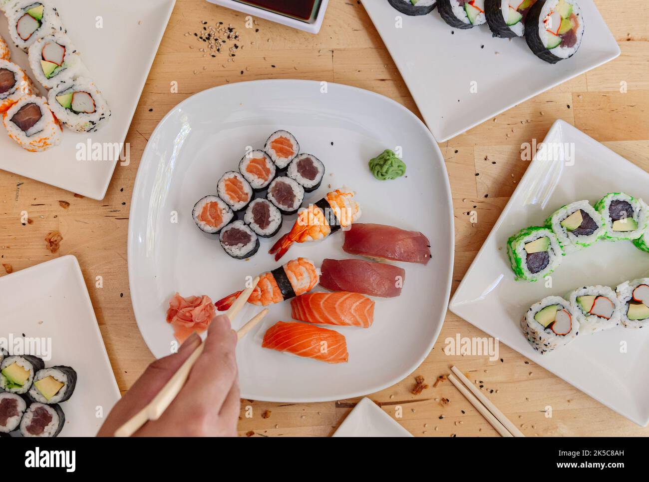 Elle se rapproche des mains prenant un morceau de sushi avec des baguettes. Fruits de mer sains et plats japonais asiatiques. Banque D'Images