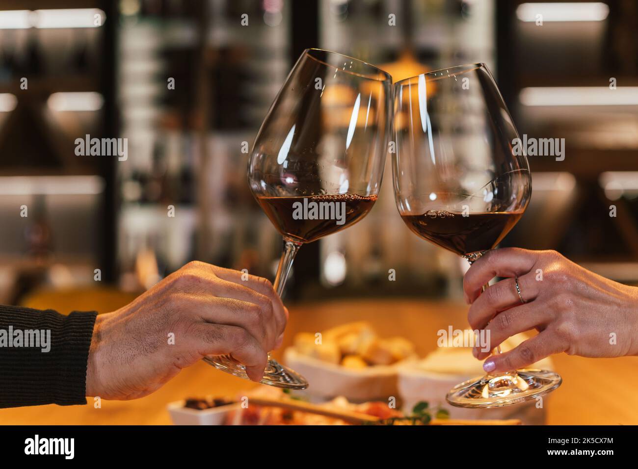 Couple romantique assis l'un en face de l'autre à la table à manger dans la salle à vin, des verres à vin et un verre de vin blanc Banque D'Images