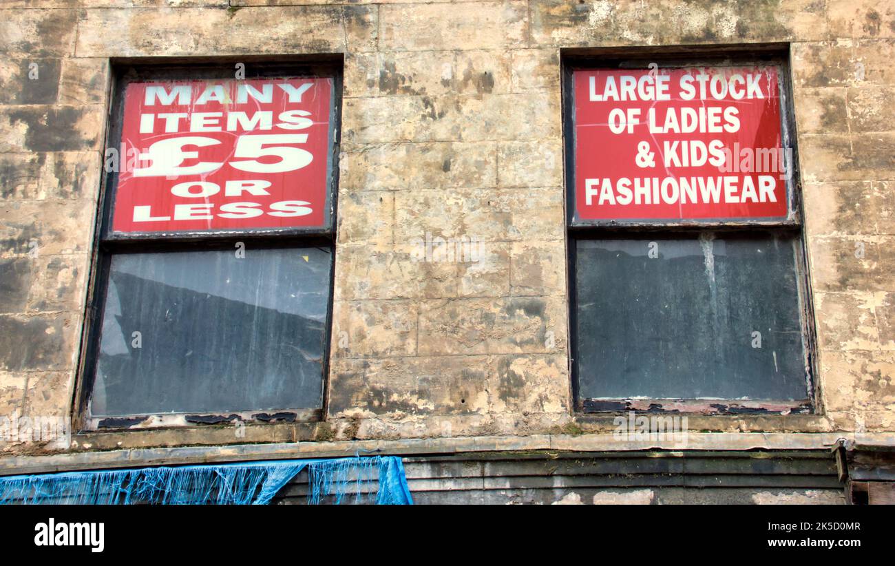 Les fenêtres publicitaires de bâtiment délabrées représentant la pauvreté et les signes d'entreprise de shopping échoués Paisley, Écosse, Royaume-Uni Banque D'Images