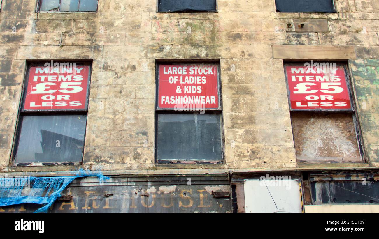Les fenêtres publicitaires de bâtiment délabrées représentant la pauvreté et les signes d'entreprise de shopping échoués Paisley, Écosse, Royaume-Uni Banque D'Images