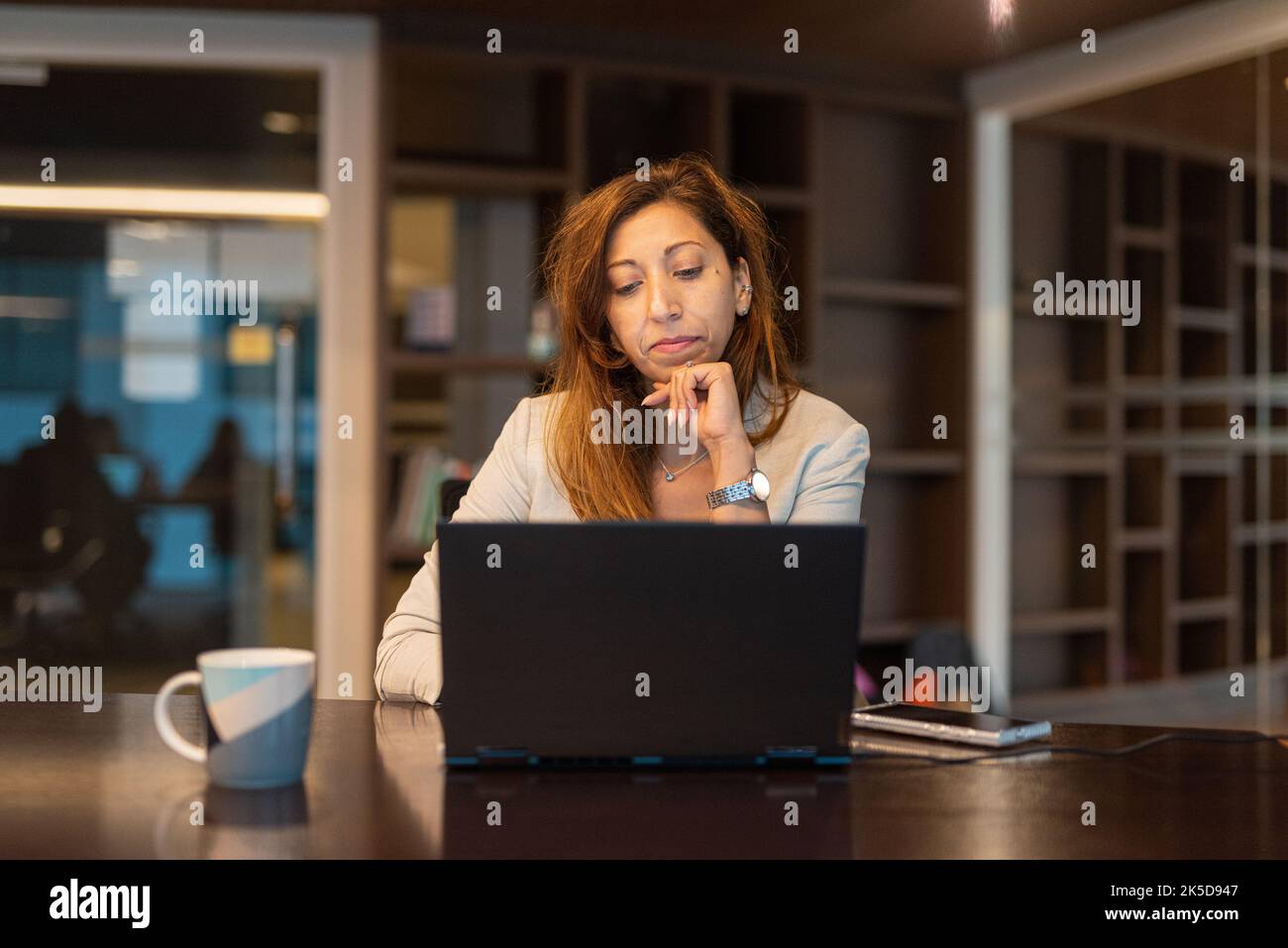 Portrait d'une femme d'affaires utilisant un ordinateur portable la nuit dans une prise de vue horizontale au bureau Banque D'Images