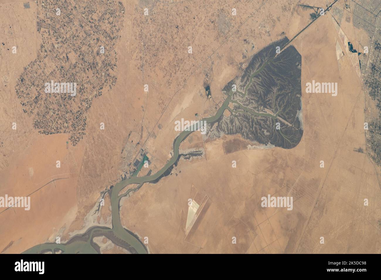 La voie navigable Khawr az-Zubayr (en bas) sépare les nations du Moyen-Orient du Koweït et de l'Iraq sur la côte du golfe Persique. En haut à gauche, se trouve la ville désertique d'Abdali, au Koweït. À droite, se trouve la ville fertile et agricole d'Abu Al-Khaseeb, en Irak. La Station spatiale internationale était en orbite à 262 miles au-dessus de l'Arabie Saoudite près de l'île-nation de Bahreïn au moment où cette photo a été prise. Banque D'Images