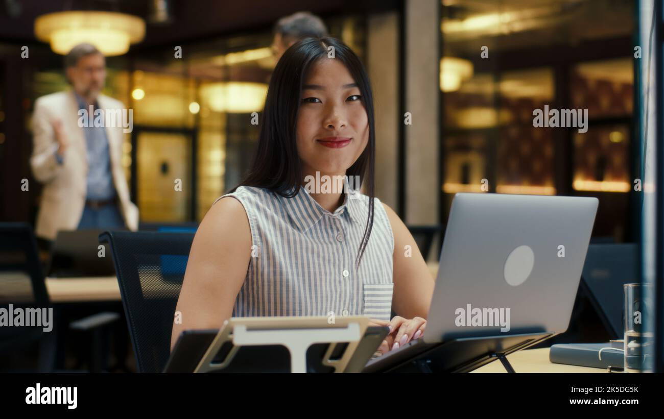 Femme d'affaires asiatique regardant la caméra tout en travaillant sur la stratégie d'entreprise dans un bureau moderne utilisant un ordinateur portable et une tablette numérique. Société de commerce électronique Banque D'Images