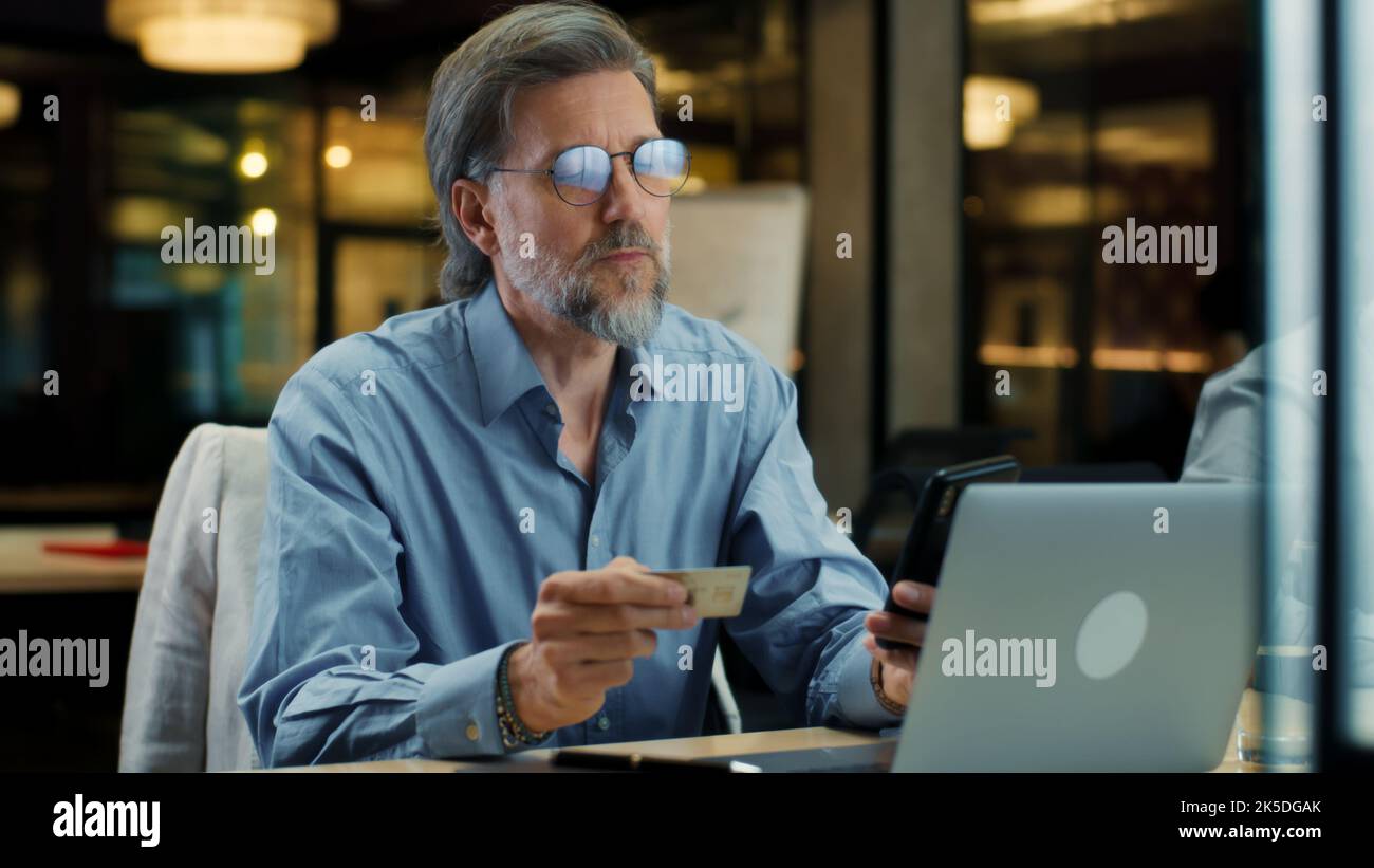 Homme d'affaires utilisant le téléphone, transférer de l'argent sur la carte bancaire, payer pour le service en ligne pendant le travail dans le bureau moderne de LA société INFORMATIQUE Banque D'Images