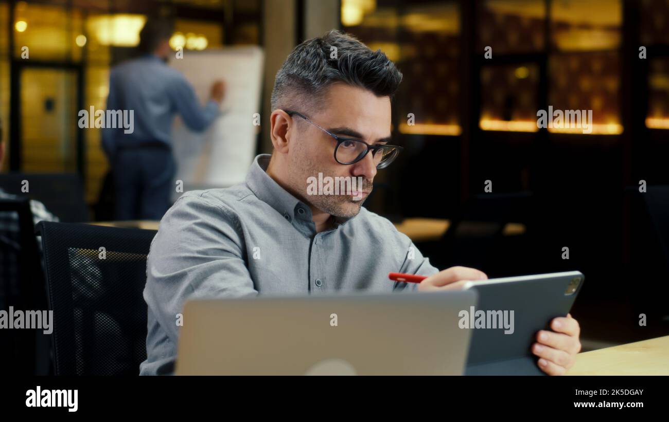 Travailleur de bureau masculin, utilisant une tablette informatique et un crayon numérique, travaillant dans un bureau moderne sur un projet de démarrage, une stratégie d'affaires ou la conception de site Web. Travaillez en entreprise INFORMATIQUE Banque D'Images