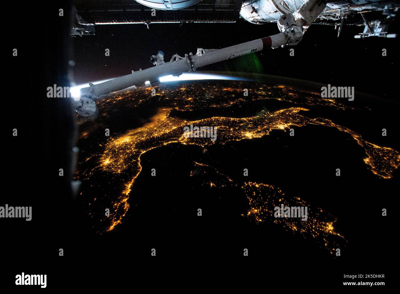 Les lumières de la ville d'Italie, y compris l'île française de Corse et les îles italiennes de Sardaigne et de Sicile, sont photographiées de la Station spatiale internationale à 261 miles au-dessus de la mer Méditerranée tout en volant dans un lever de soleil orbital. Dans le premier plan supérieur, se trouve une partie du bras robotique Candarm2. Banque D'Images