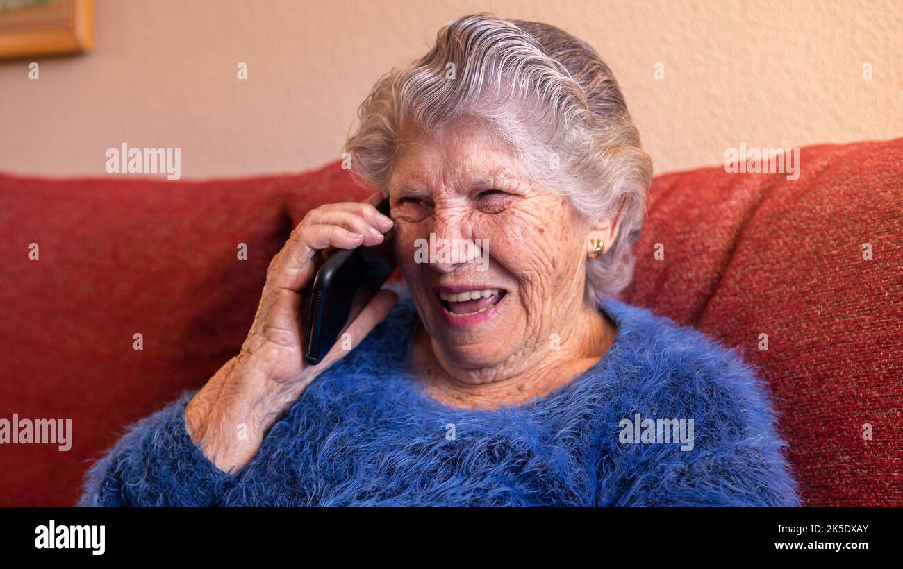 Grand-mère souriante parlant sur téléphone portable. Grand-mère qui fait une conversation téléphonique. Femme âgée utilisant un smartphone pour parler pendant Banque D'Images