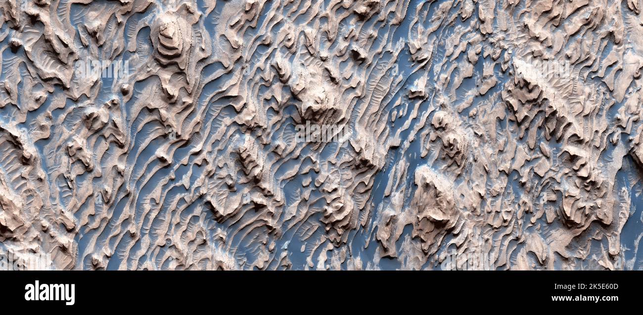 Paysage martien. Cette image de HiRISE montre un exemple classique de roche sédimentaire martienne dans le cratère Danielson. Les nombreuses couches de roche sont régulièrement espacées, formant des étapes, ce qui implique une série de couches de chapeau fortes alternant avec des couches plus faibles. À petite échelle, une grande partie de la roche est fortement fracturée. Parce que les pièces fracturées s'emboîent parfaitement, cela s'est produit après que le dépôt s'est tourné vers la roche. L'image couleur améliorée montre le terrain à moins de 1 km (moins d'un mile) de haut en bas. Une version optimisée unique des images de la NASA. Crédit: NASA/JPL/UArizona Banque D'Images
