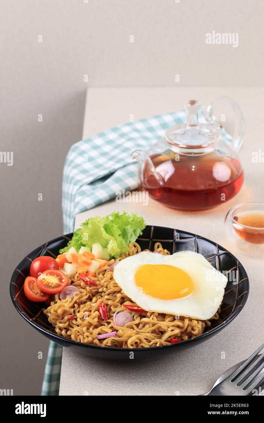 Indomie Goreng ou Mie Goreng, indonésien populaire Instant Noodle. Servi avec un œuf de poule, de la tomate et de la laitue Banque D'Images