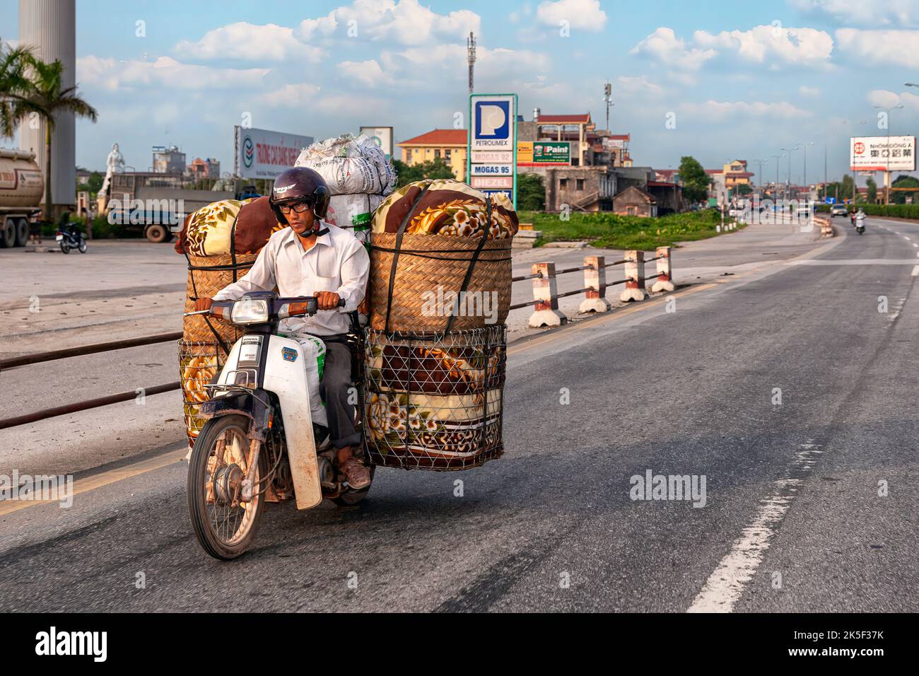 Moto chargée passant la petite ville de Hai Phong à l'autoroute de Hanoi, Vietnam Banque D'Images