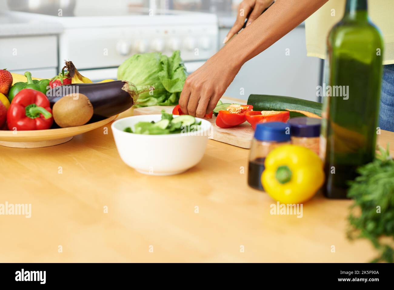 Une femme qui prépare une salade dans sa cuisine. Banque D'Images
