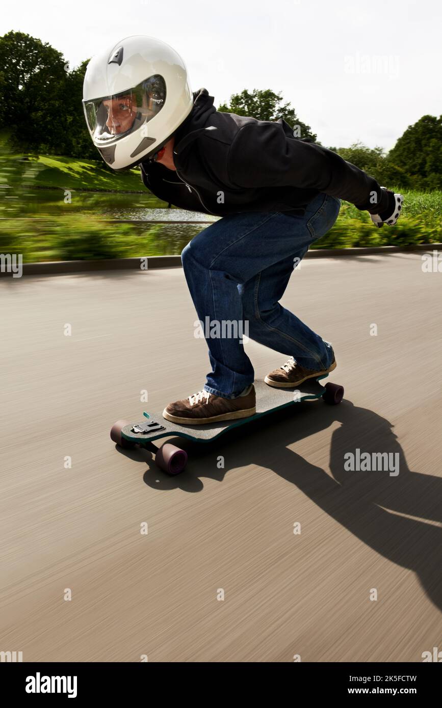 À la poursuite de la prochaine poussée d'adrénaline. Un homme skate sur une route sur son plateau. Banque D'Images
