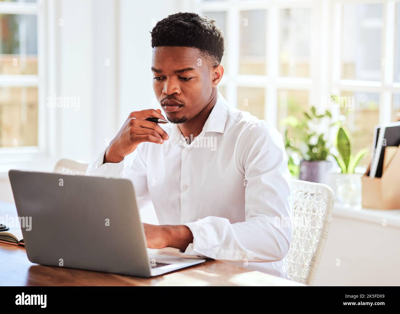 Bureau, ordinateur portable et homme d'affaires africain travaillant sur un projet et faisant des recherches sur Internet. Technologie, jeune et professionnel noir homme lisant Banque D'Images