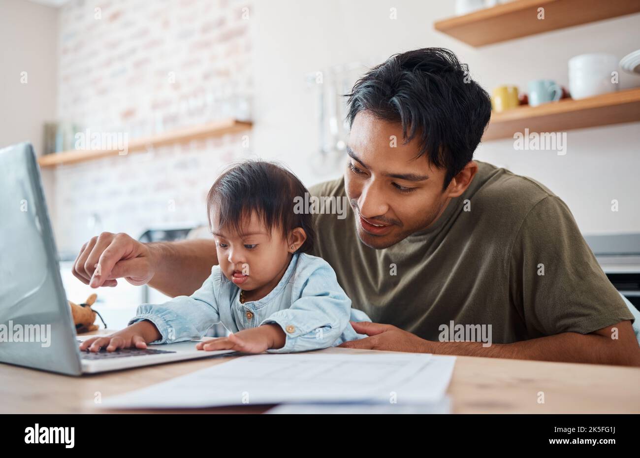 Le père, le syndrome de Down bébé et l'ordinateur portable dans la cuisine liant avec l'enfant tout en travaillant à la maison. Père asiatique jouant avec un nouveau-né enfant avec génétique Banque D'Images