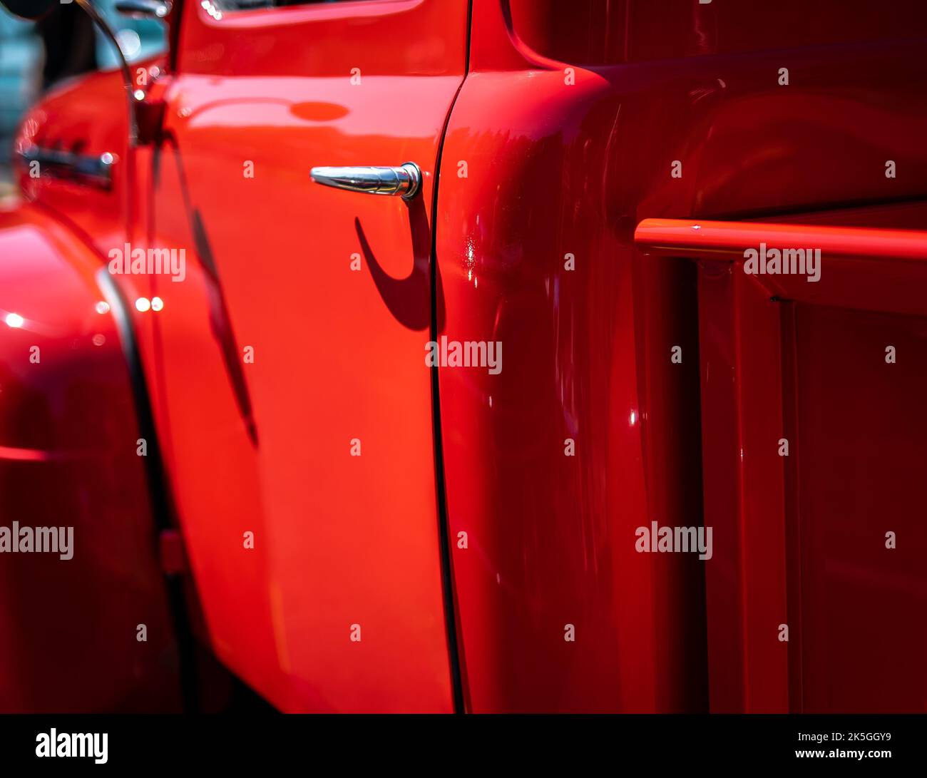 Camionnette antique restaurée rouge vif à un salon de l'automobile sur une journée ensoleillée. Détail de la porte conducteur avec faible profondeur de champ focale image.chadow Banque D'Images
