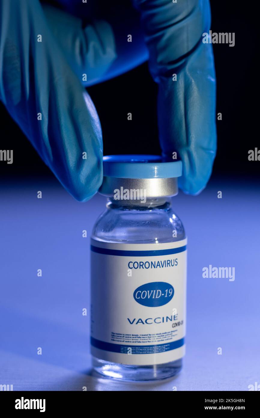 Mise au point de vaccins. Prévention Covid-19. Inoculation du coronavirus. Immunisation en cas de pandémie. Main médecin dans un gant de protection bleu avec flacon de dose W Banque D'Images