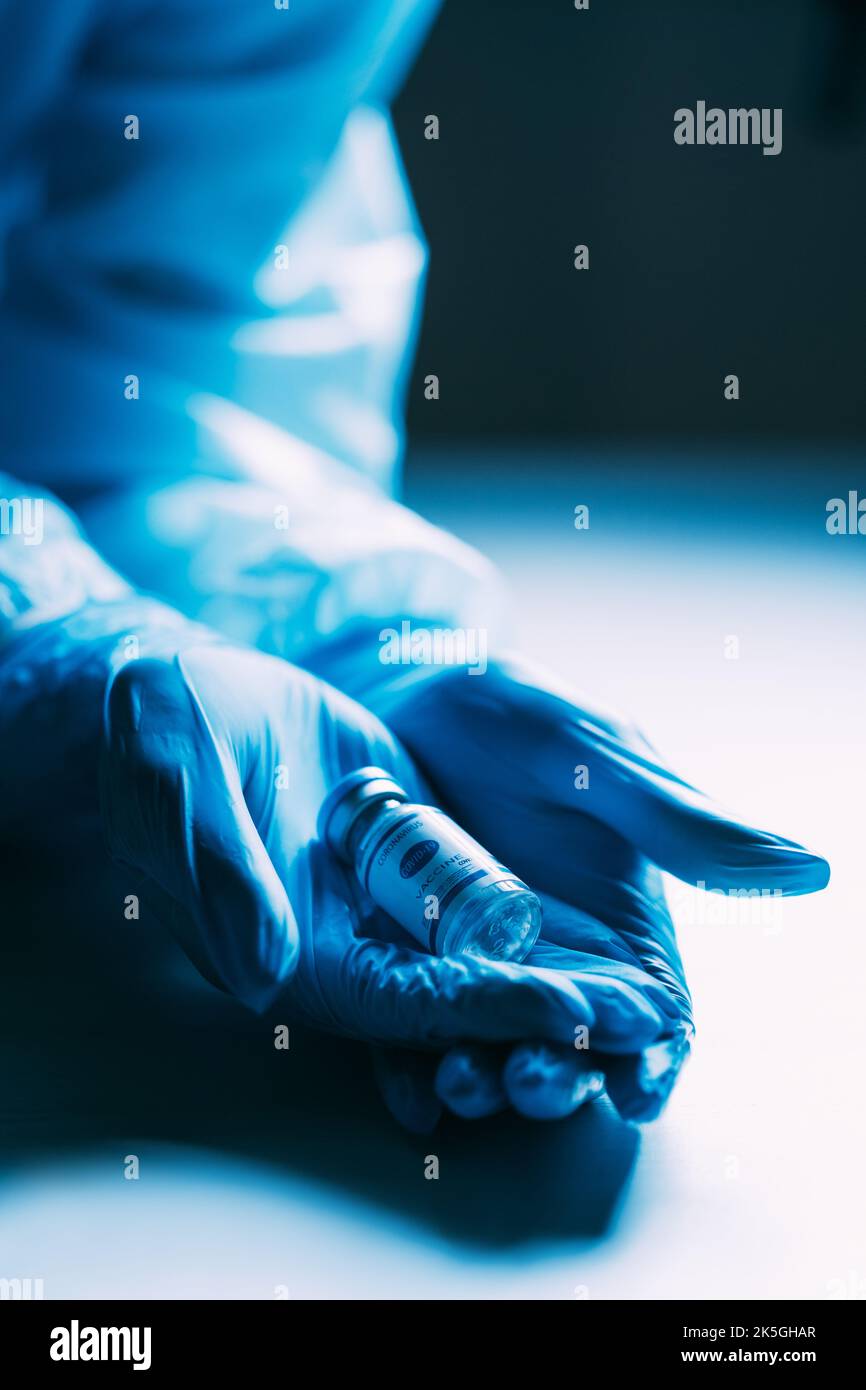 Vaccin contre le coronavirus. Inoculation pandémique. Anticorps Covid-19. Protection des soins de santé. Flacon de dose avec étiquette dans les mains du médecin dans des gants bleus epi on Banque D'Images
