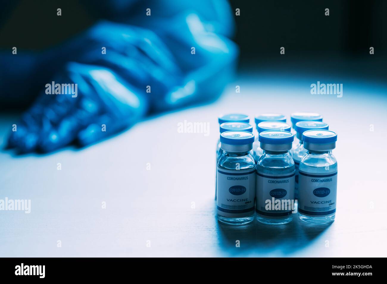 Vaccin Covid-19. Immunisation en cas de pandémie. Inoculation du coronavirus. Essai clinique. Flacons de dose bleus flacons avec main médecin dans un gant de protection ppe Banque D'Images