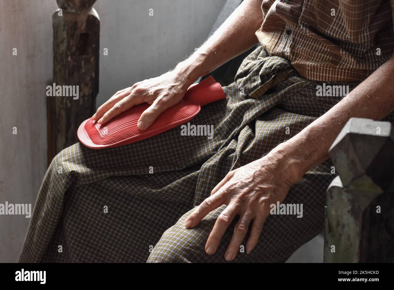 Douleur aux cuisses chez un patient asiatique de sexe masculin. Concept de douleur musculaire, sciatique ou nerf sciatique. Thérapie par sac d'eau chaude en caoutchouc. Banque D'Images