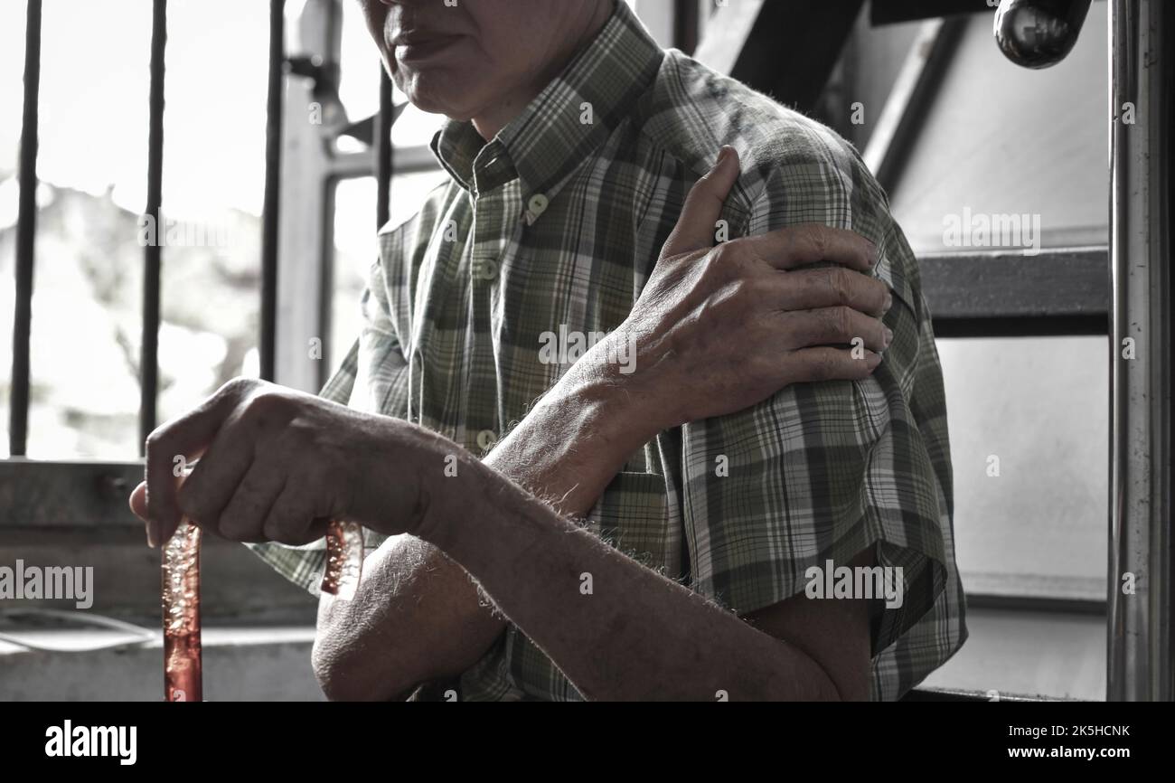 Douleur dans le bras supérieur de l'homme aîné d'Asie du Sud-est. Concept de l'épaule gelée. Banque D'Images