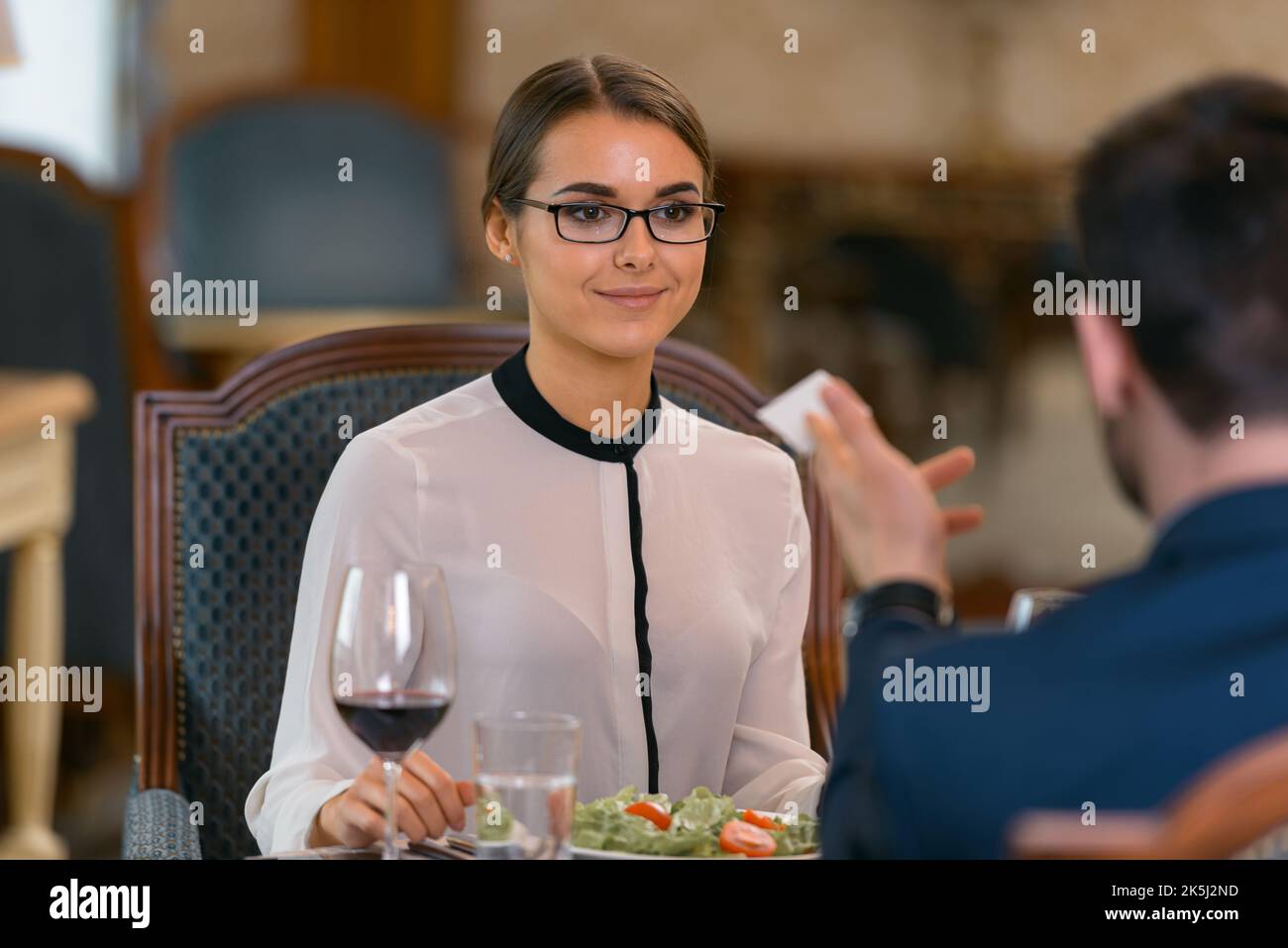 Homme d'affaires donnant sa carte de visite à une femme tout en dînant dans le restaurant de l'hôtel de luxe Banque D'Images