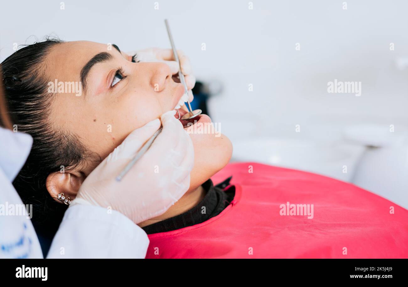 Gros plan d'un dentiste professionnel nettoyant les dents de la patiente, gros plan d'un spécialiste dentaire nettoyant les dents d'un patient. Vue latérale du dentiste Banque D'Images