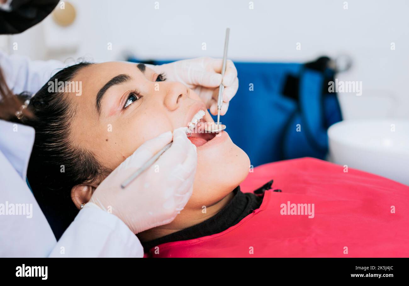 Gros plan d'un spécialiste dentaire nettoyant les dents d'un patient. Gros plan du dentiste professionnel nettoyant les dents des patientes, vue latérale du dentiste Banque D'Images