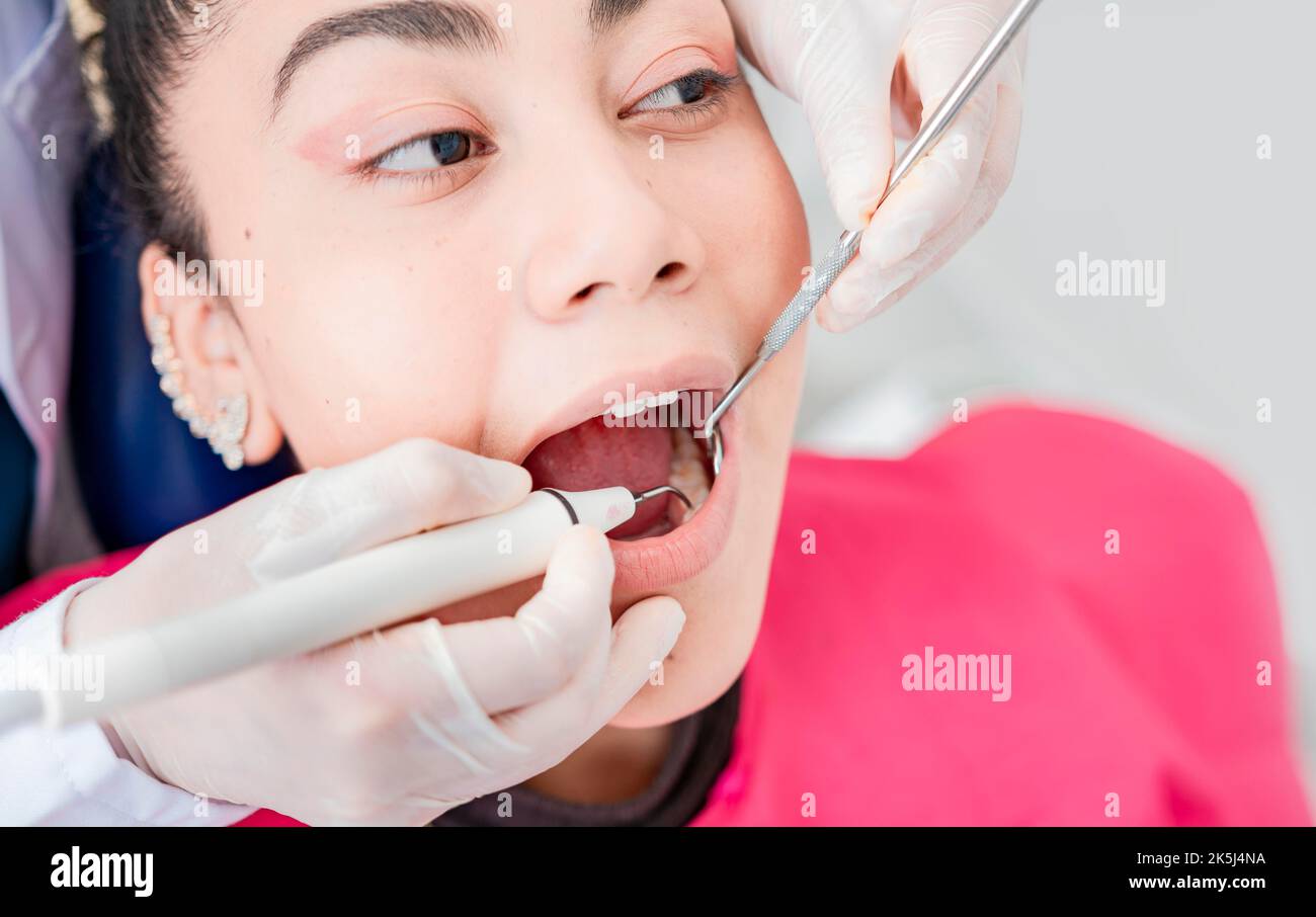 Gros plan d'un dentiste vérifiant un patient avec une pelle hydraulique et un miroir dentaire, d'un dentiste vérifiant un patient avec une pelle hydraulique et un miroir dentaire, d'un patient vérifié par Banque D'Images