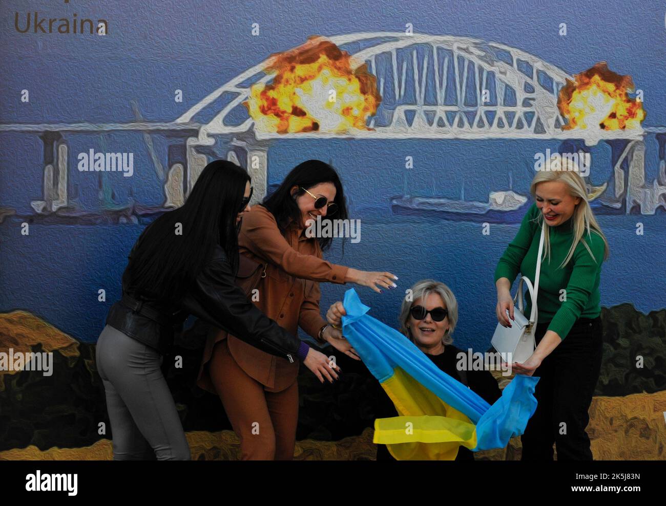 Kiev, Ukraine. 08th octobre 2022. Les femmes arborent le drapeau ukrainien pour prendre une photo sur l'arrière-plan de la disposition du timbre qui représente le pont de Kerch en feu. Sur 8 octobre, sur le pont de Crimée reliant la Russie à la péninsule occupée par elle, après l'explosion, un incendie fort a éclaté. (Photo par Sergei Chuzavkov/SOPA Images/Sipa USA) crédit: SIPA USA/Alay Live News Banque D'Images