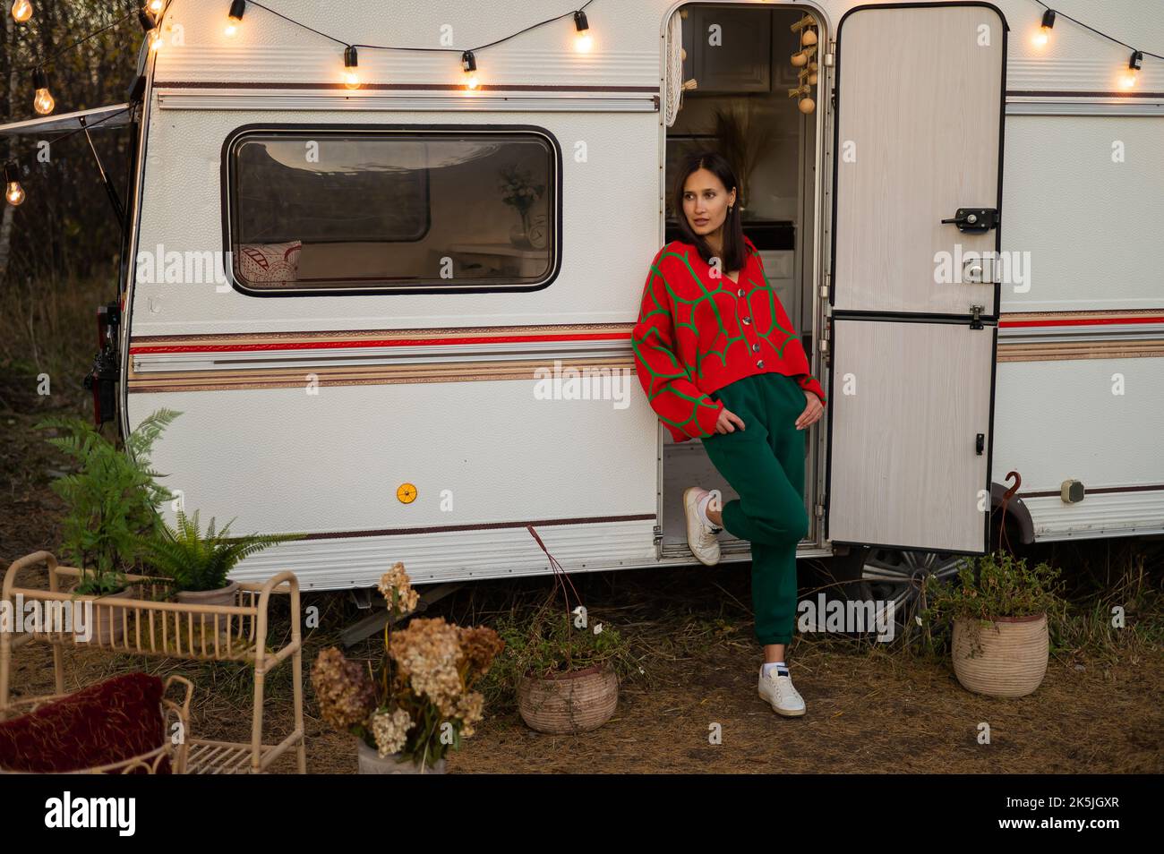 Une femme caucasienne en pull tricoté rouge surdimensionné voyage à motorhome en automne. Banque D'Images