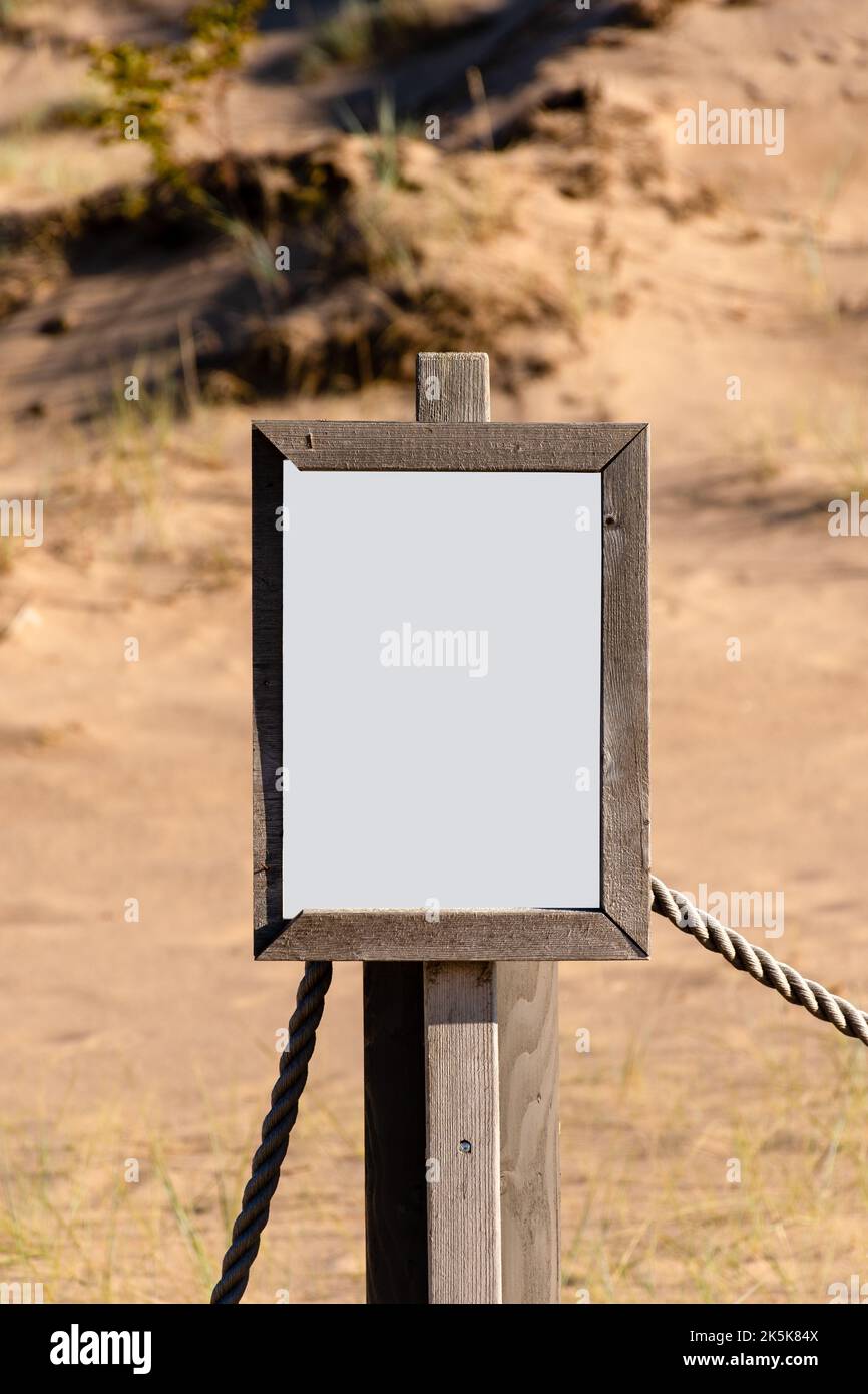 Panneau blanc vide avec cadre en bois partiellement cassé sur une plage de sable Banque D'Images