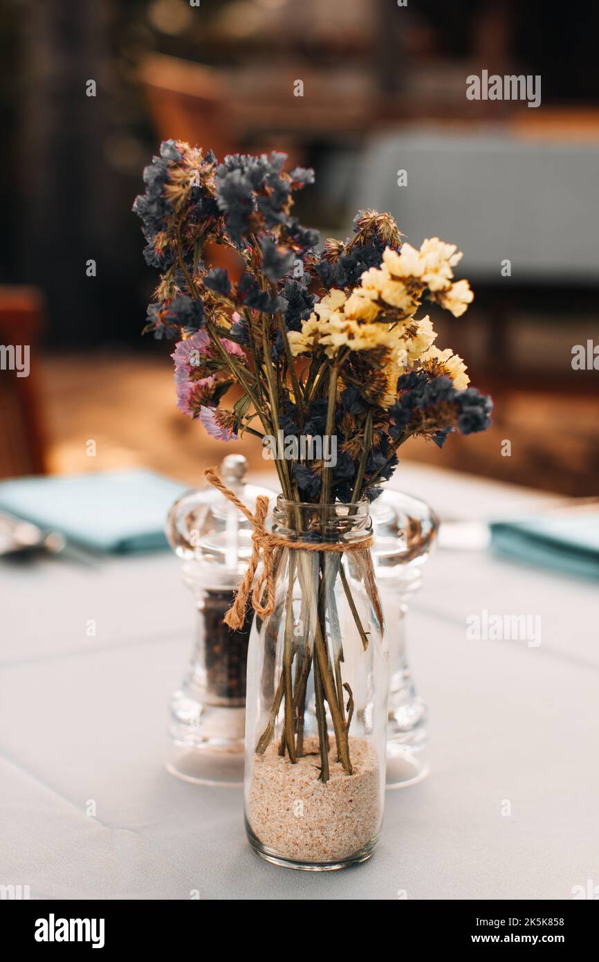 Fleurs bleues jaunes séchées en automne dans un vase en verre sur la table Banque D'Images