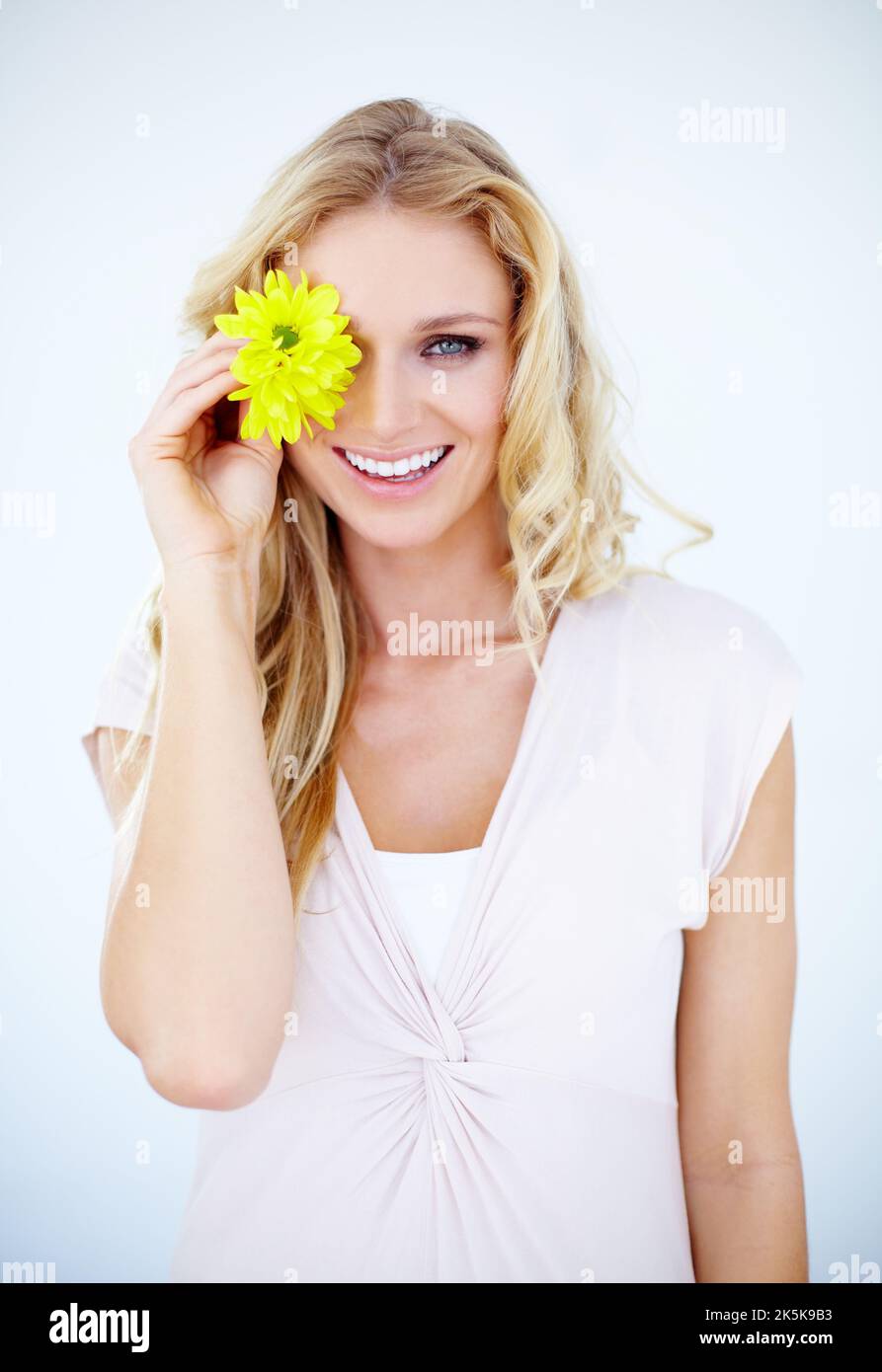 Vue positive sur la beauté naturelle. Jolie jeune femme isolée sur blanc et recouvrant son œil d'une Marguerite. Banque D'Images