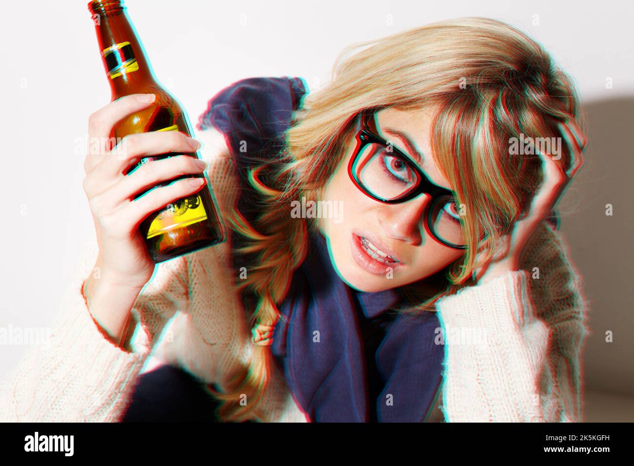 Mi commençant à voir double. Une jeune femme assise sur le sol avec une bière dans la main. Banque D'Images