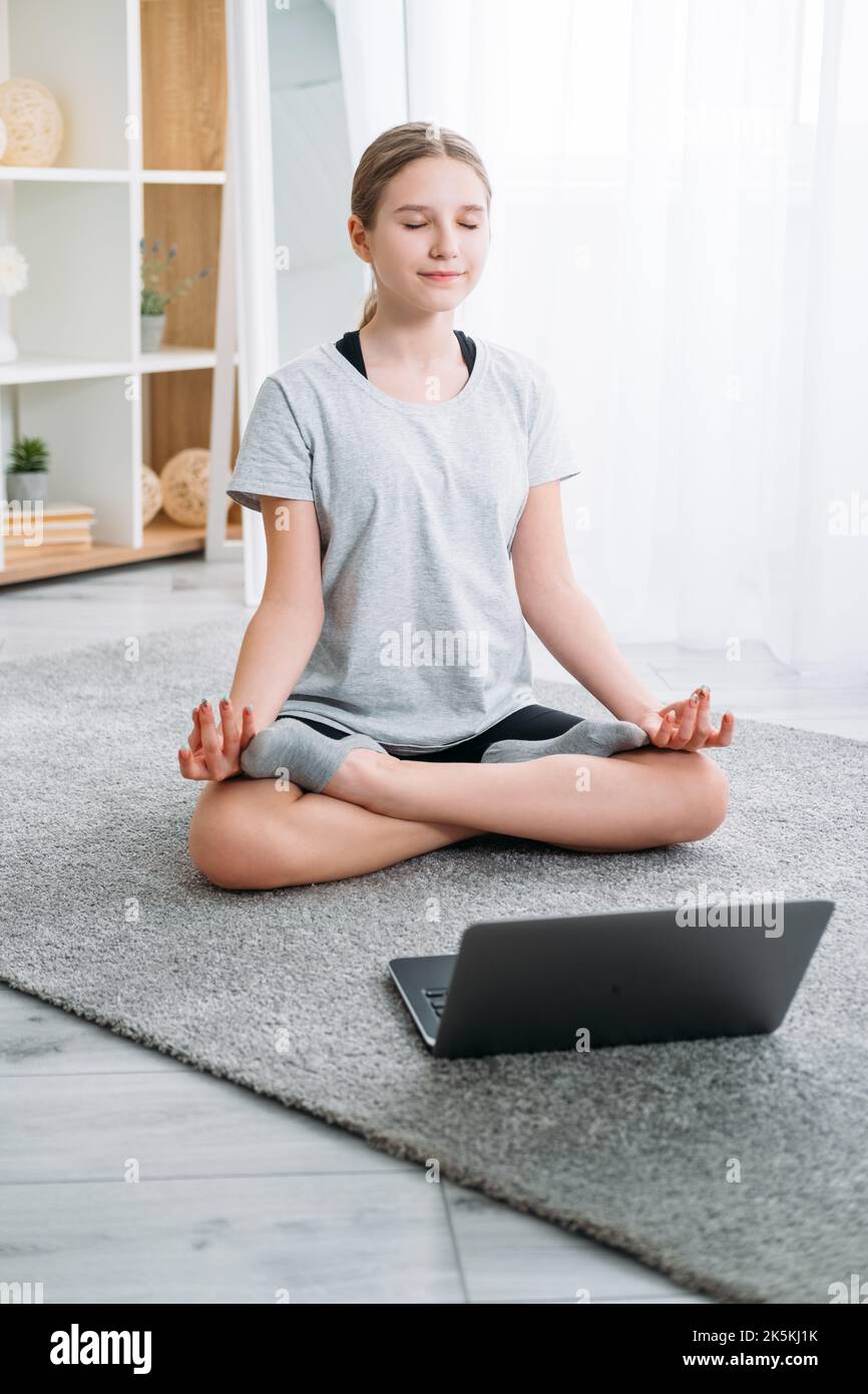 enfants à la maison yoga en ligne méditation fille avec ordinateur portable Banque D'Images