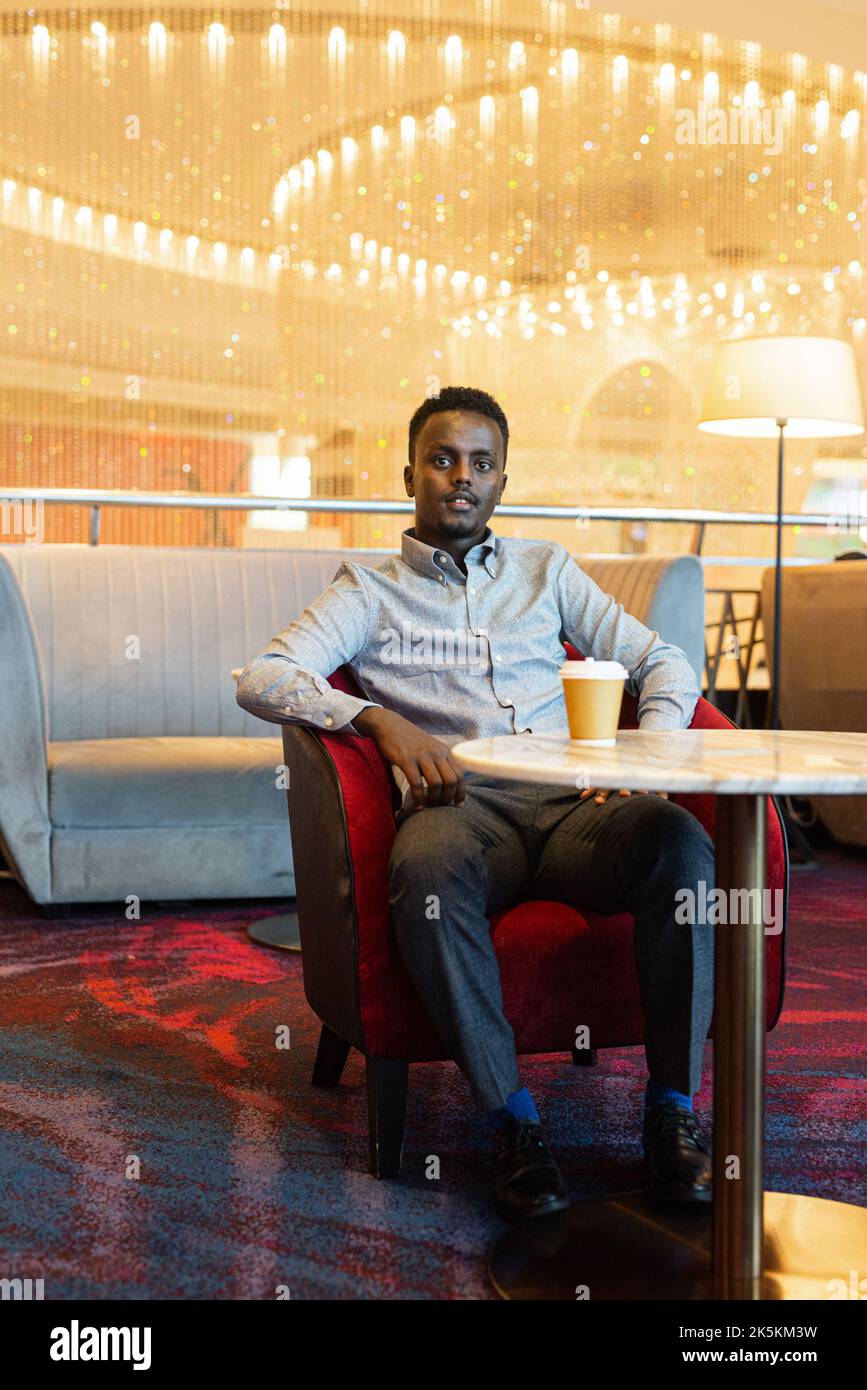 Portrait d'un beau jeune africain ayant une pause-café en étant assis Banque D'Images