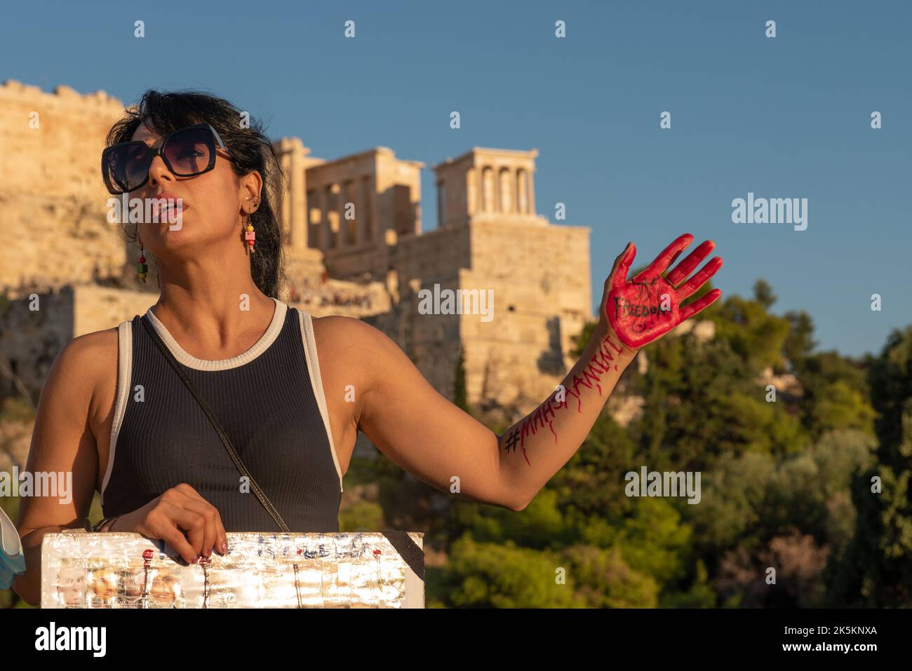 Athènes, Grèce. 8th octobre 2022. Une femme qui avait écrit avec des peintures rouges et noires les noms « ahsa Amini » et « liberté » sur son bras et sa paume démontre devant l'Acropole d'Athènes en solidarité avec le combat pour la liberté des Iraniens après la mort de Mahsa Amini après sa détention par la police morale pour violation les règles du hijab. Crédit: Nicolas Koutsokostas/Alay stock photo. Banque D'Images