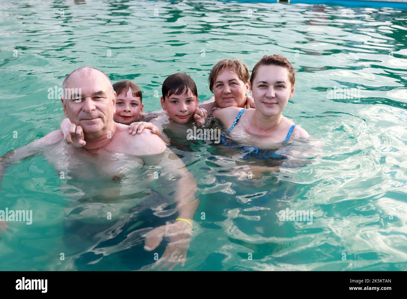 Famille posant dans la piscine ouverte en été Banque D'Images