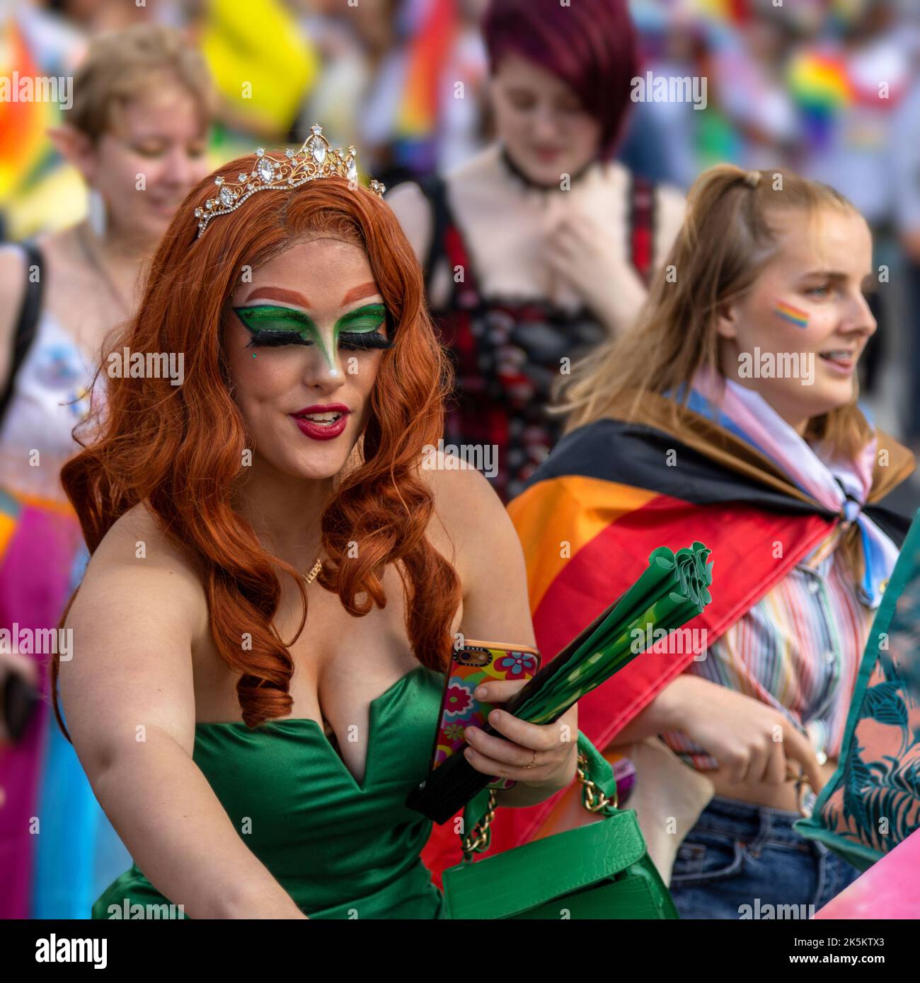 Une femme attirante aux cheveux rouges et à la robe verte participe au défilé de la Birmingham Pride avec ses amis. Banque D'Images