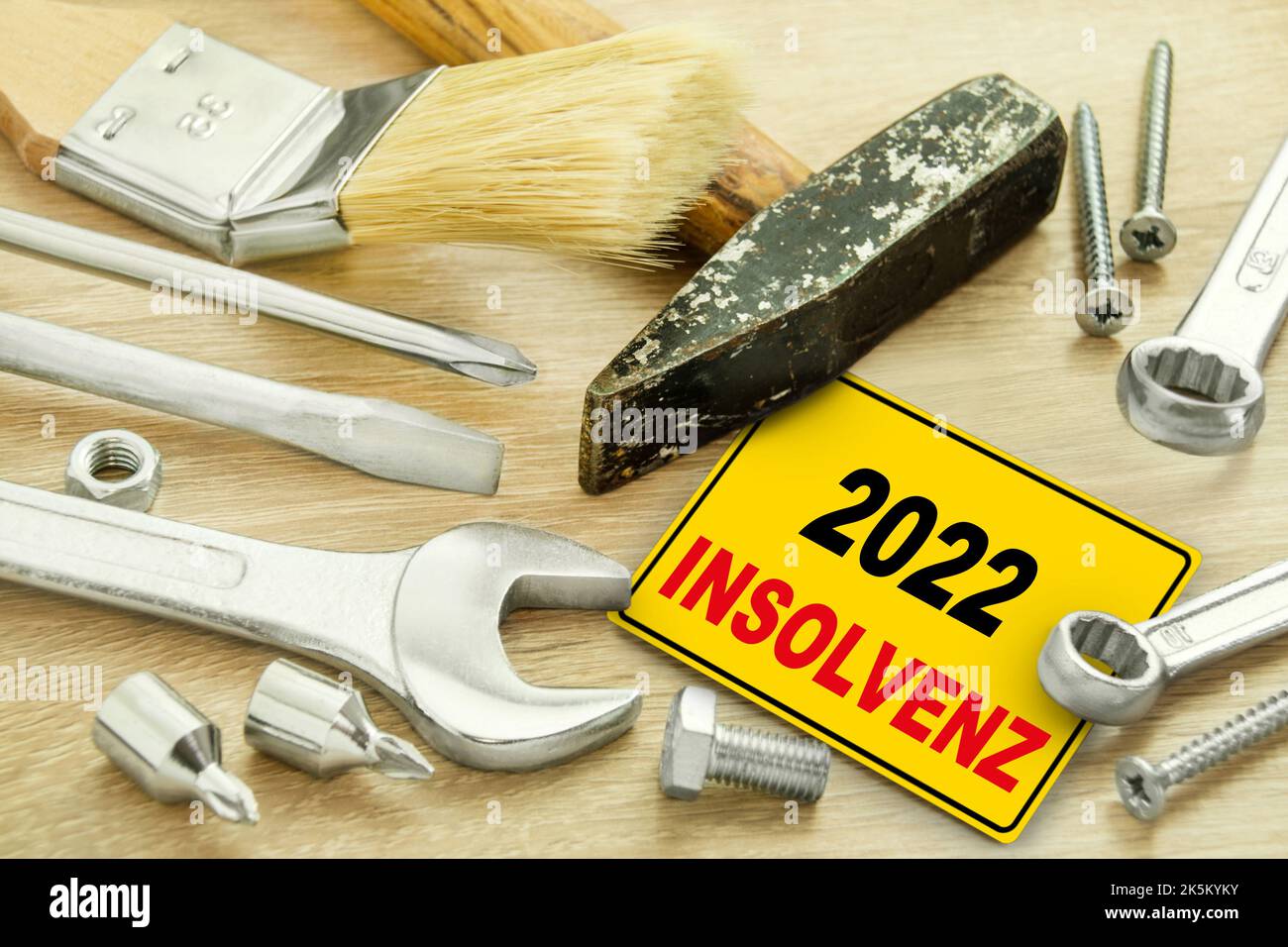 Deutsches gelbes Schild mit Insolvenz im Jahr 2022 und Werkzeug auf Holz Banque D'Images