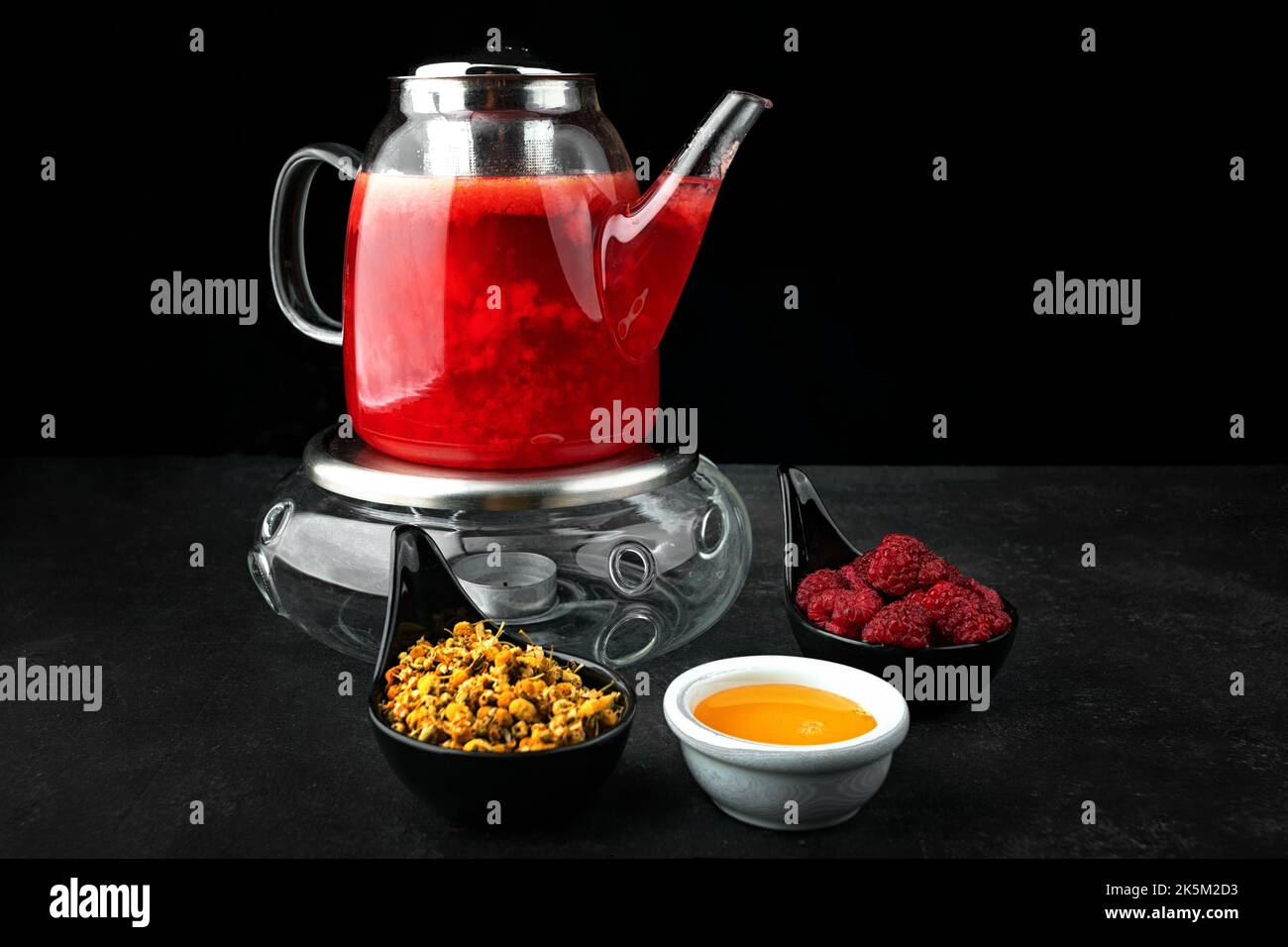 Thé aux framboises et au miel dans une théière en verre Banque D'Images