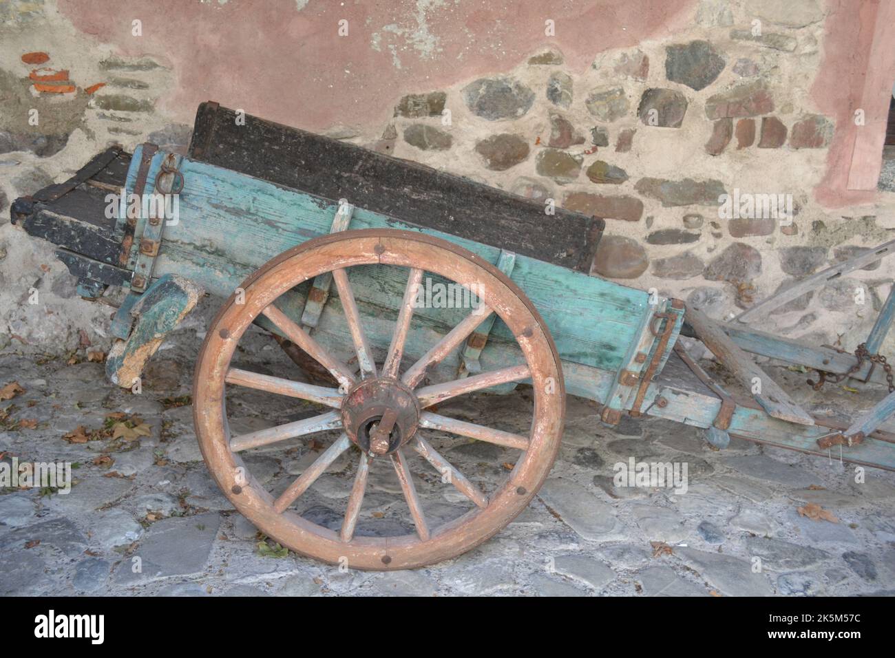 Vue rapprochée de l'ancienne remorque de cavalerie en bois à deux roues placée près de l'ancien mur en arrière-plan. Banque D'Images